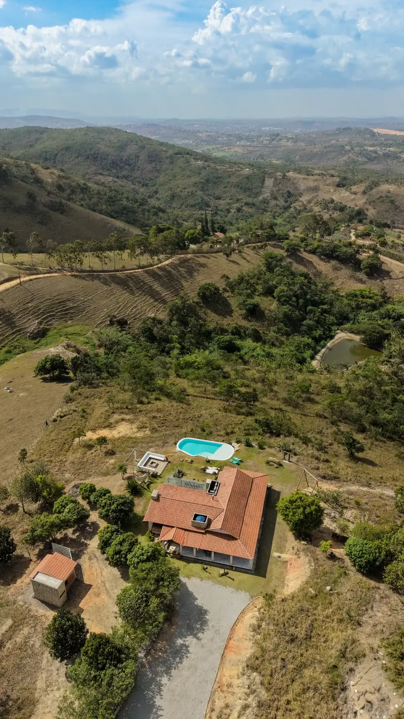 Vista aérea da casa, do acesso e das colinas ao redor