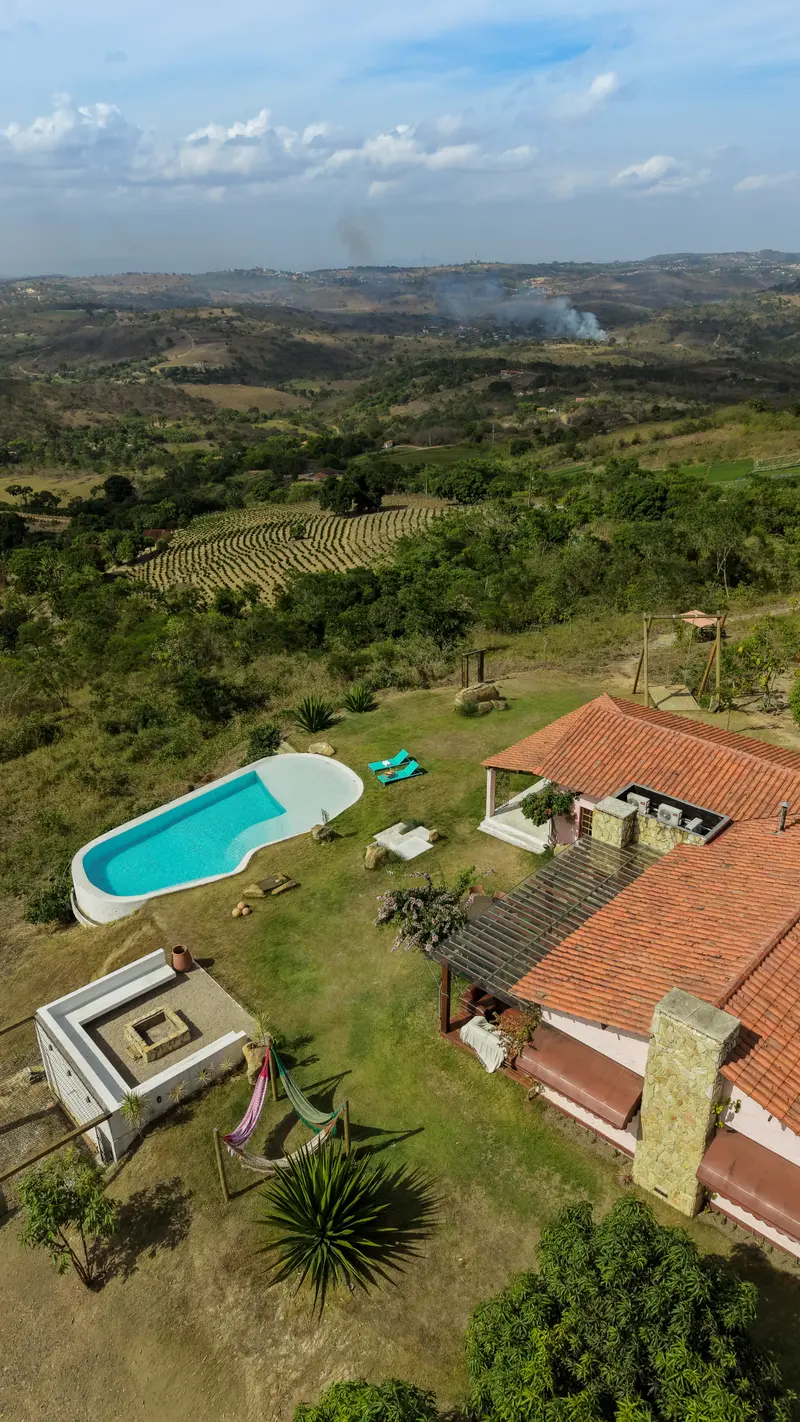 Vista aérea da casa, da piscina e do espaço da fogueira em meio ao vale