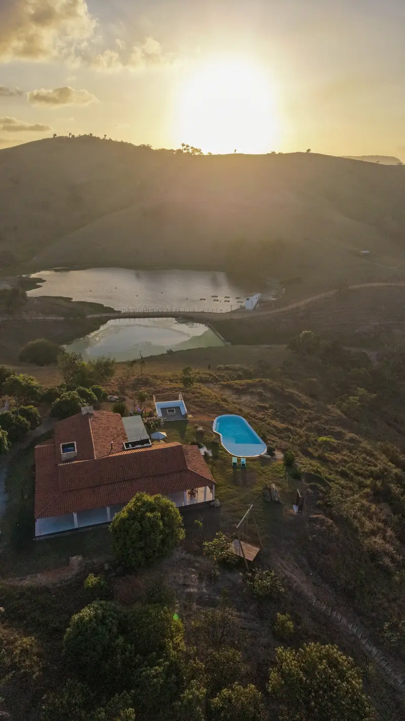 Sol se pondo sobre uma colina, com o açude e a casa abaixo