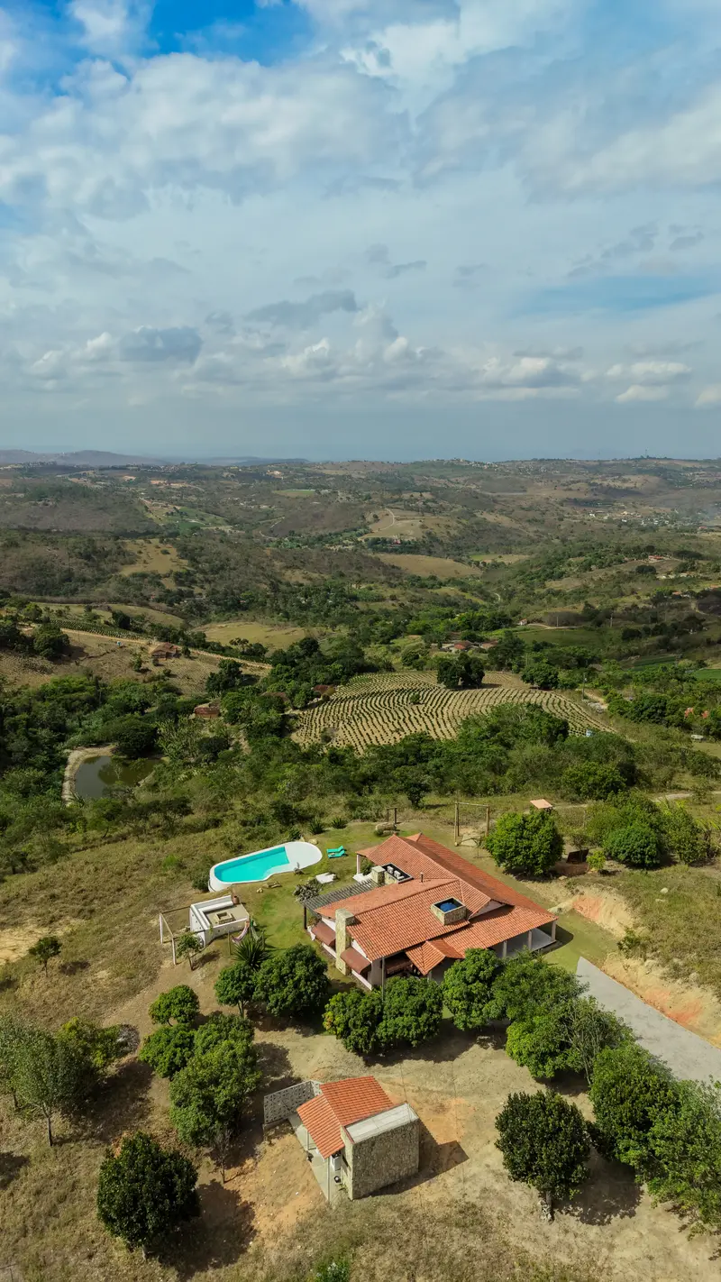 Vista aérea da casa pequena no meio de um vale amplo sob grande céu
