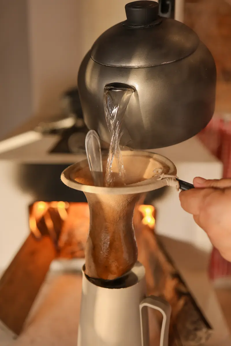 Café sendo coado com água de uma chaleira