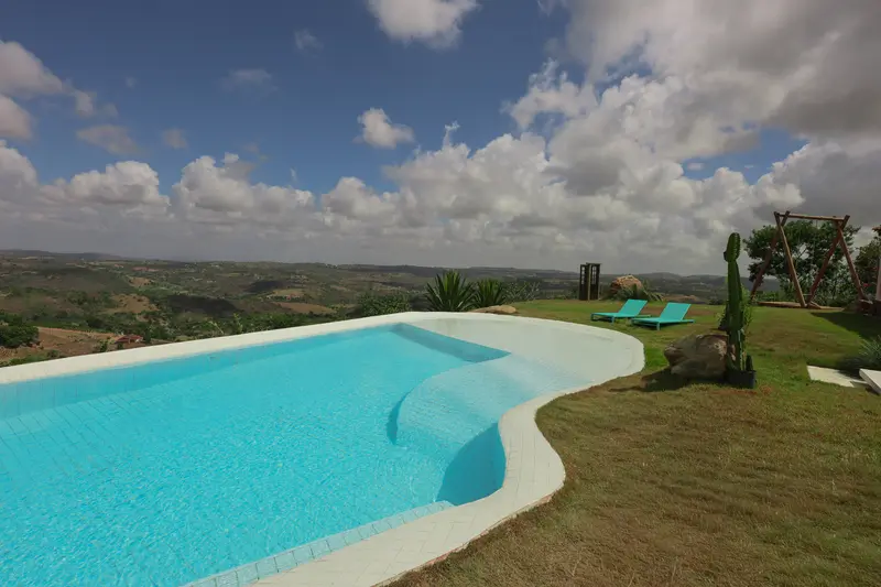 Piscina da Casa Pedra da Lua com o vale e um céu azul de nuvens esparsas ao fundo
