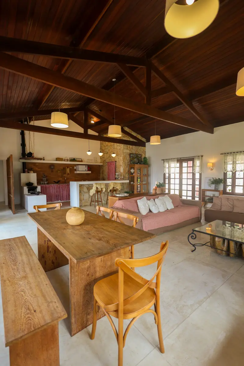 Sala com teto alto de madeira, lareira de pedra e sofá